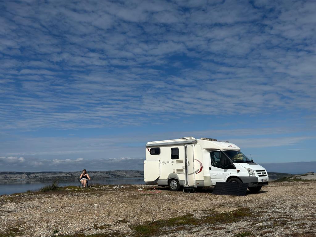 Matkailuauto ja nainen vieressä.